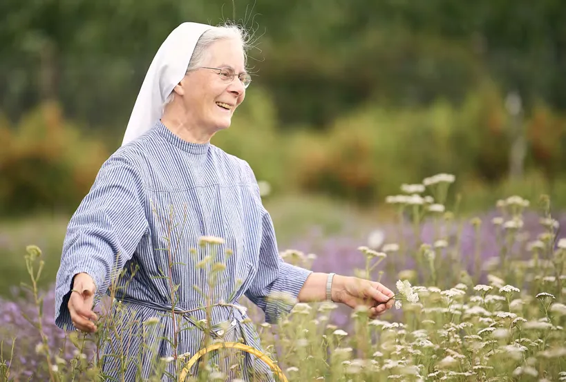 Eine Schwester geht lachend durch eine Blumenwiese